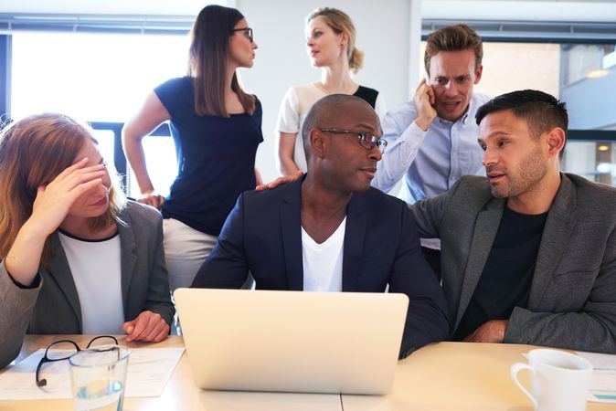 Stressed out business associates huddled around a laptop in an office