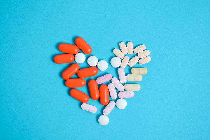Top view of pIlls in heart shape on blue background