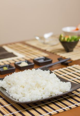 Rice plate ready to make Japanese sushi rolls, with principal ingredients in the background