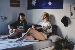 Lesbian couple playing guitar on bed