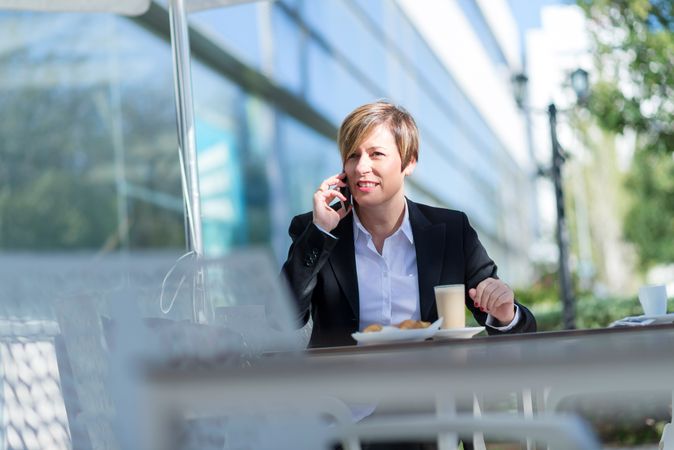 Female sitting outside with coffee and cell phone