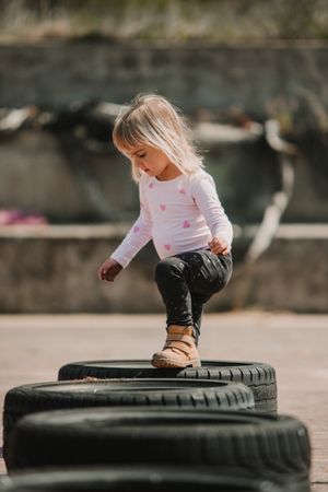 Cute girl walking on car tires