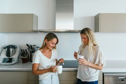 Women with coffee chatting in kitchen