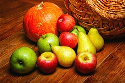 Autumnal fruit and squash on wooden table with wicker basket