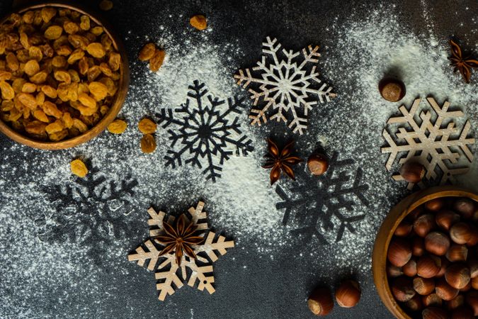 Flour scattered on decorative snow flakes with bowls of baking ingredients
