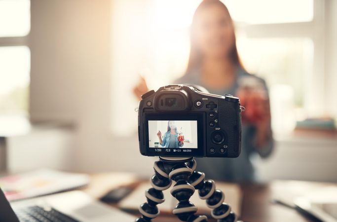 Woman filming herself in her bright home office