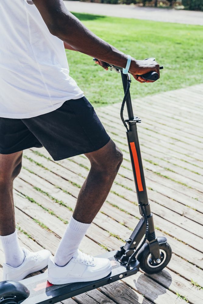Black man riding on electric scooter in park