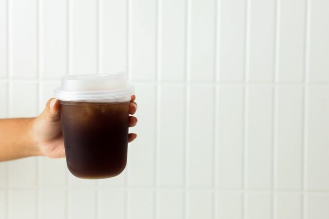 Female Hand Holding To Go Plastic Cup with Iced Coffee