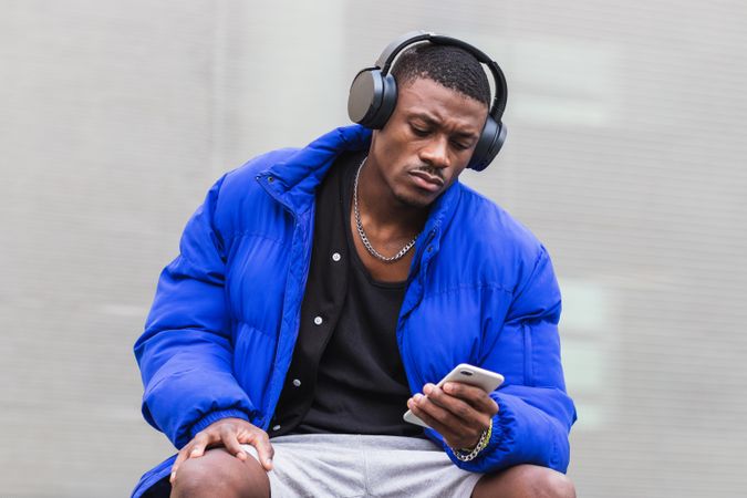 Black man with headphones on smartphone in city