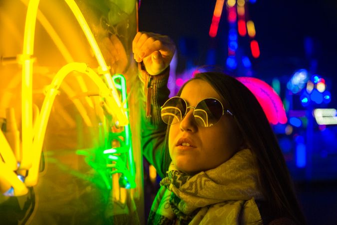 Stylish young woman near illuminated board