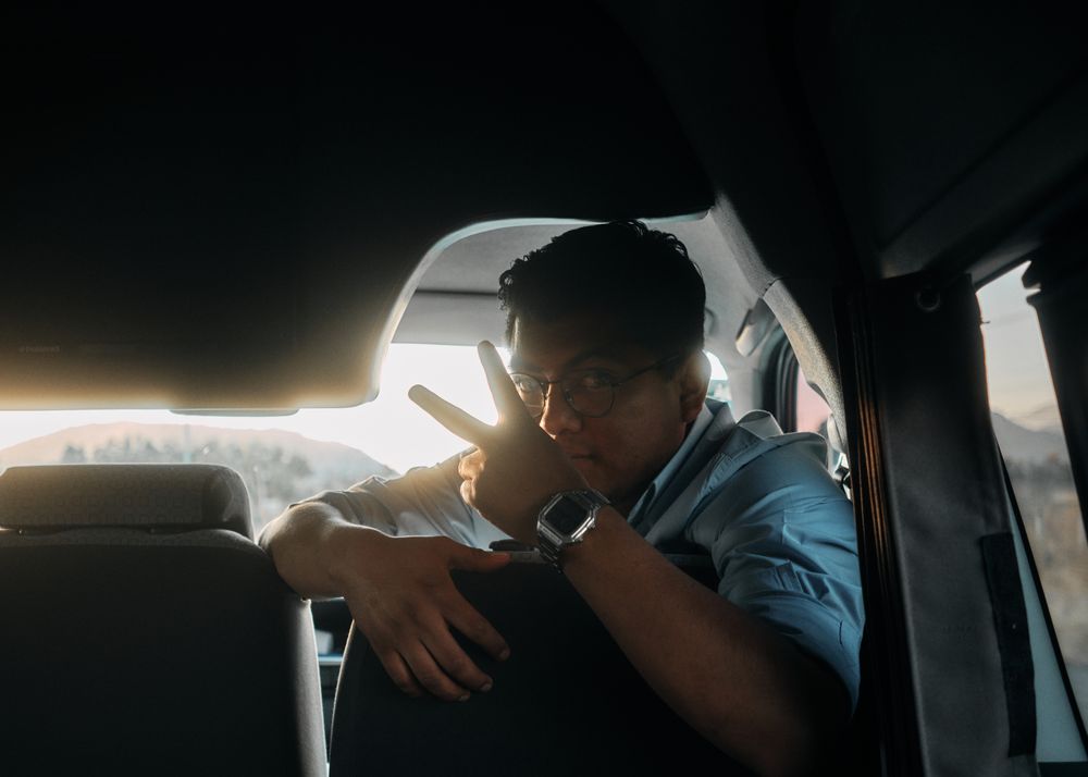 Man making peace sign looking back from passenger seat