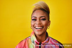 Studio shot of smiling Black woman in colorful 80s windbreaker jacket and gold jewelry bYdaG4