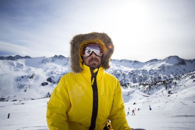Man in yellow parka and goggles spending a winter day at a ski resort