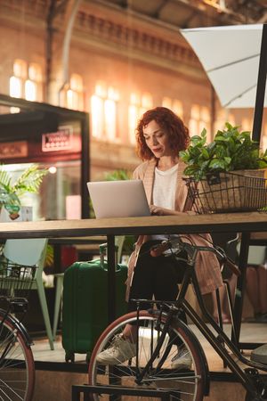 Cheerful young woman working on laptop in cafe
