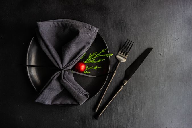 Holiday table setting with dark cutlery, plate and table with ornaments