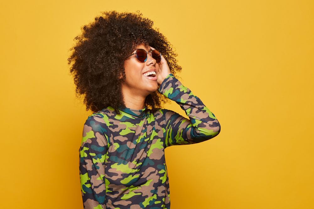 Black woman in sunglasses on bright backdrop
