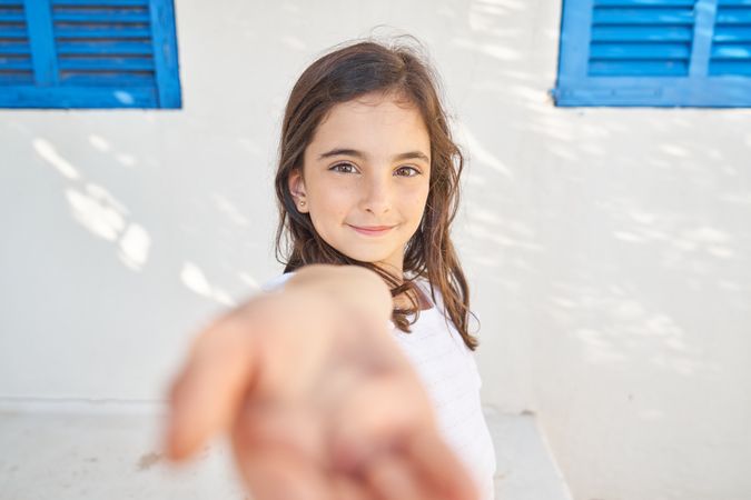 Smiling child standing near building wall
