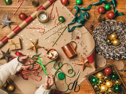 Festive scene with candy canes, star tree ornaments, ribbon, wrapping paper, woman cutting ribbon