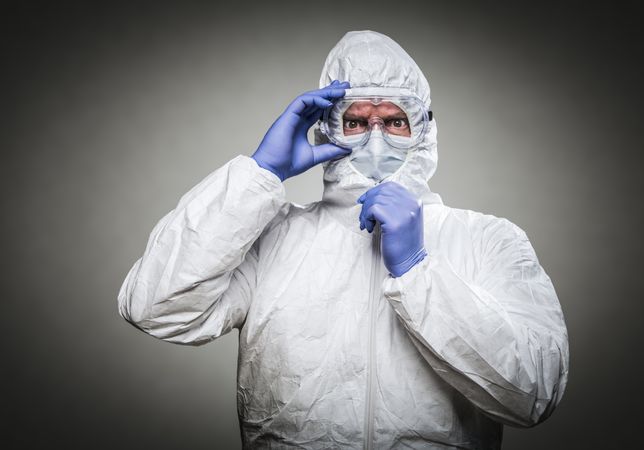 Man With Intense Expression Wearing HAZMAT Protective Clothing Against A Gray Background.