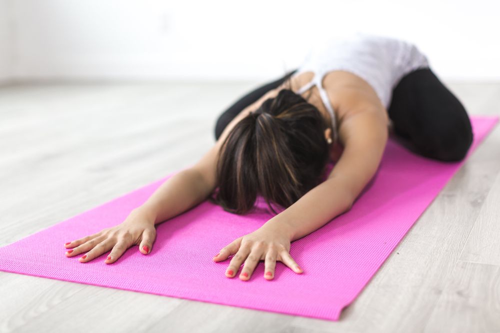 Young woman doing yoga on pink Pilate