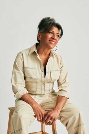 Woman in boiler suit smiling and sitting down in a studio
