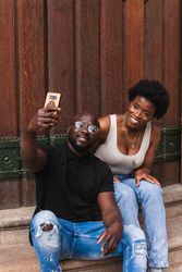 Black positive couple taking selfie together on cellphone