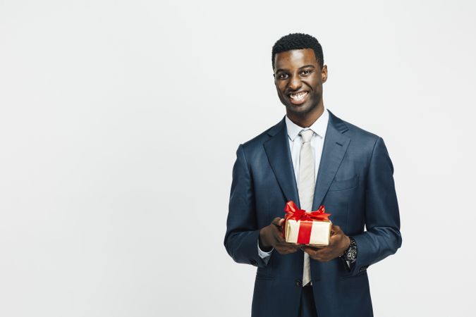 Professional Black man smiling while holding a wrapped present