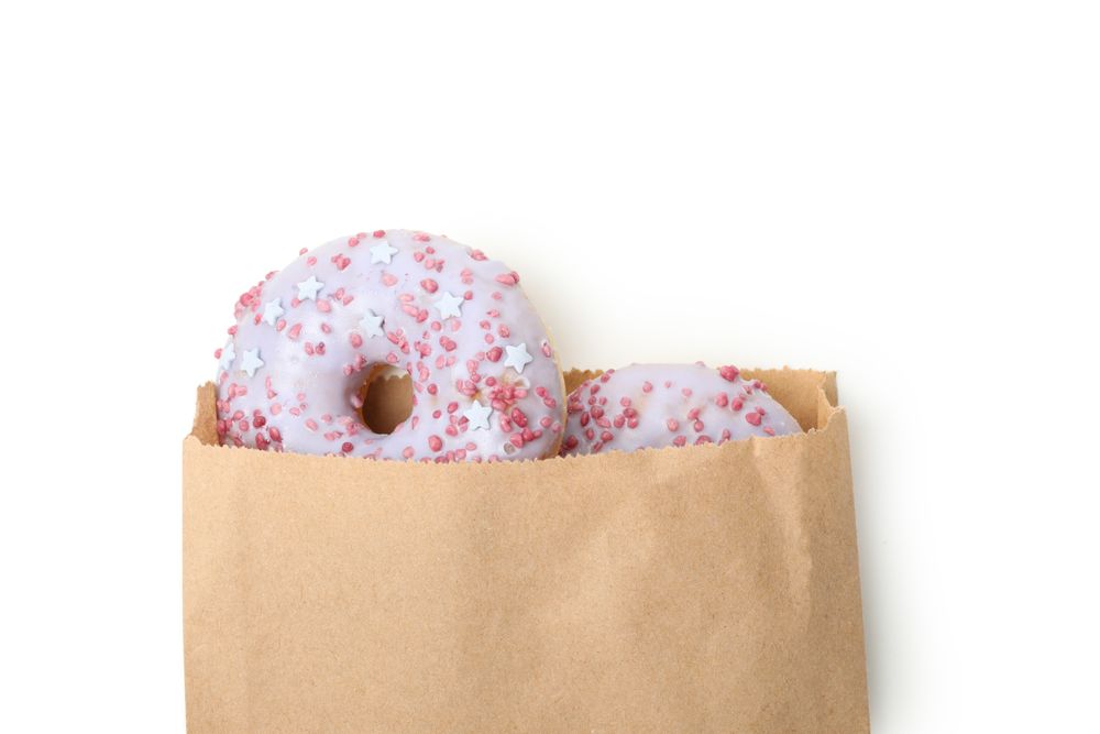 Paper bag with donuts isolated on plain background