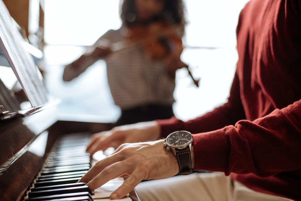 Man playing piano near woman playing violin in studio