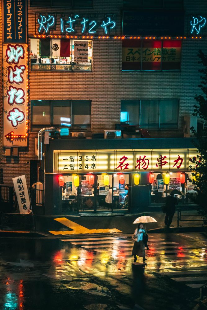Woman holding an umbrella walking on pedestrian lane during night time