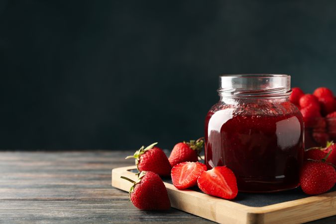 Composition with strawberry jam on wooden table, space for text