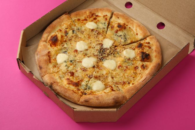 Cheese pizza in carton box on violet background
