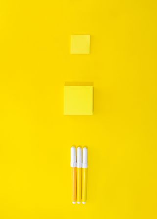 Three pens and post it notes on yellow background