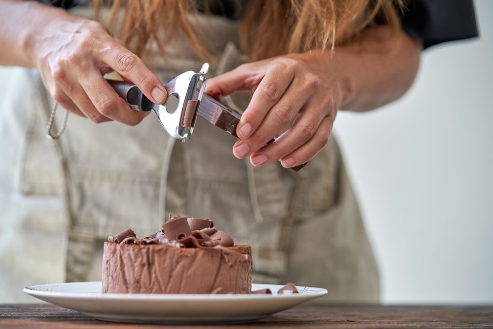 Chef decorating chocolate cake with shavings