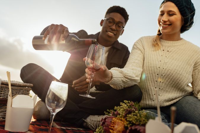 Man serving wine to his girlfriend on picnic