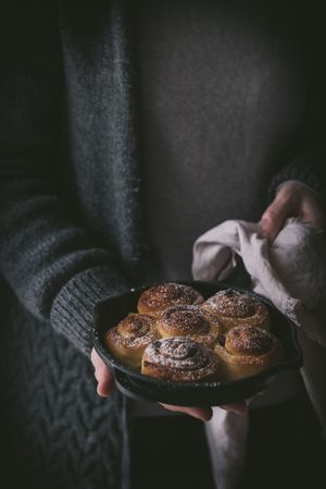 Crop woman holding cinnamon rolls
