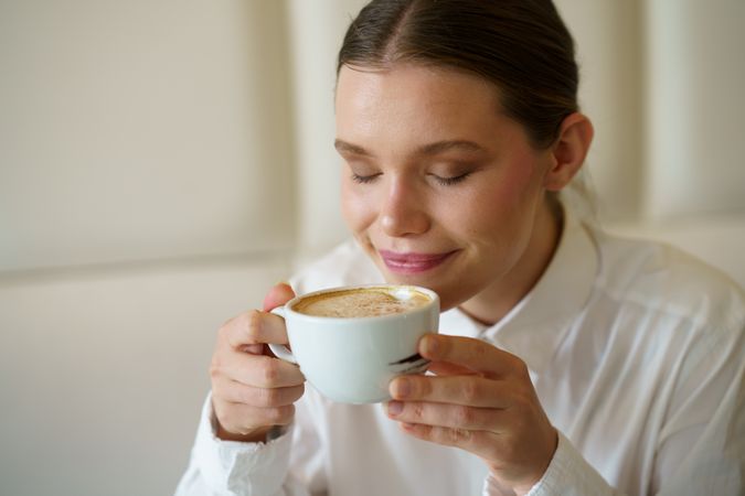 Woman smelling a delicious coffee in a cafeteria