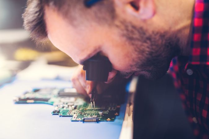 Man soldering motherboard at workplace
