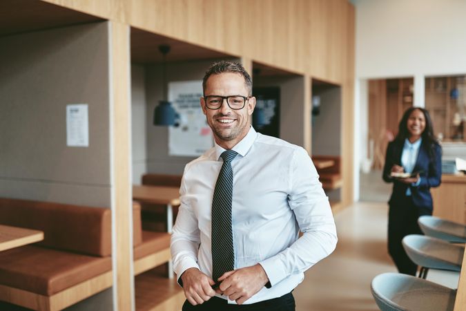 Smiling man in tie standing in open modern office