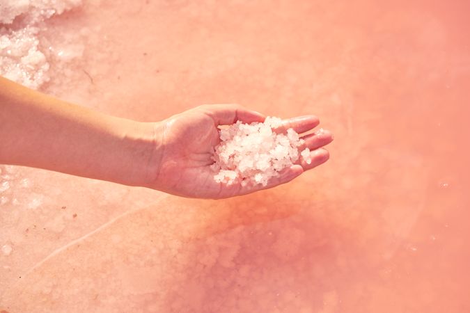 Female holding healing salt pile in pink water