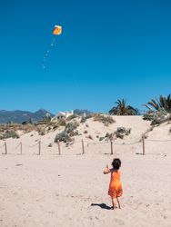 Toddler girl playing with kite on sandy beach