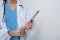Mid shot of doctor standing in light hospital room with copy space