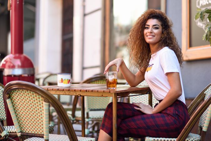 Arab woman in casual clothes drinking a soda on cafe patio