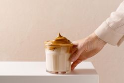 Female hand holding the glass of dalgona coffee