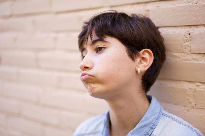 A contemplative young person with short hair is shown against a neutral background