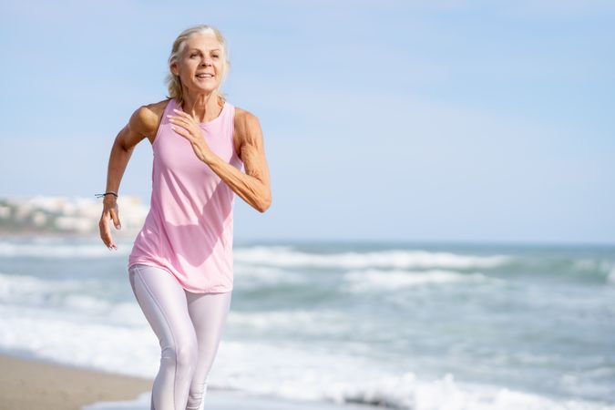 Mature female in sports gear running along beach