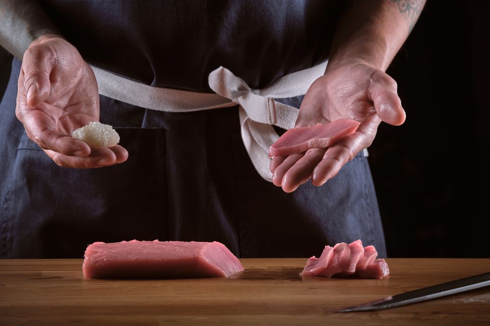 Male shushi man hands preparing different pieces of makis