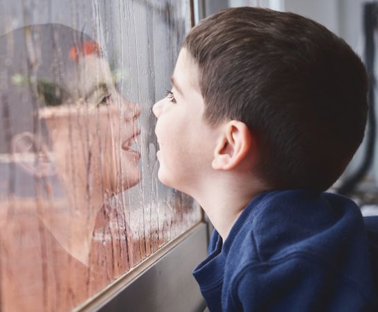 Boy breathing on wet glass