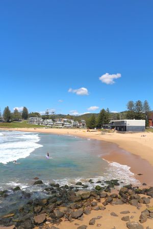 Beachside view of peaceful coastline with gentle waves and blue sky during sunny day
