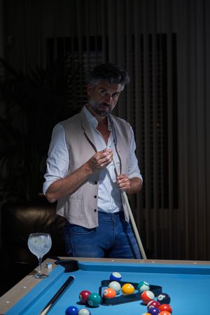 Adult male applying chalk on billiard cue stick